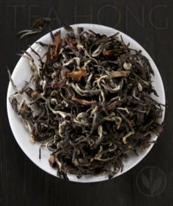 The beautiful small leaves of Oriental Beauty, spotted with tiny furry pekoe young leaf shoots and deeply oxidised red colour young leaves