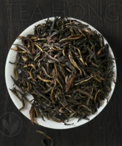 On a round white small dish filled with short and stout tealeaves in various shades of dark brown.