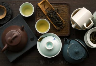 A scoop of tealeaves with 4 different infusion vessels and a few small teacups with tea