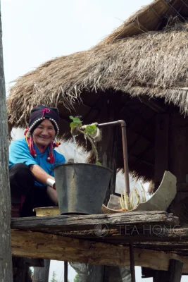 A woman of an indigenous tribe — Tai — smiles to us as we walk by her simple home