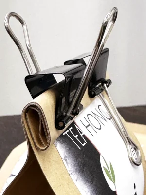 Closeup of the folding of the opening of a bag clipped seal using butterfly clips