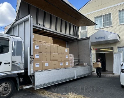 Worker moving a Tea Hong export carton onto a truck, which is already loaded with similar cartons