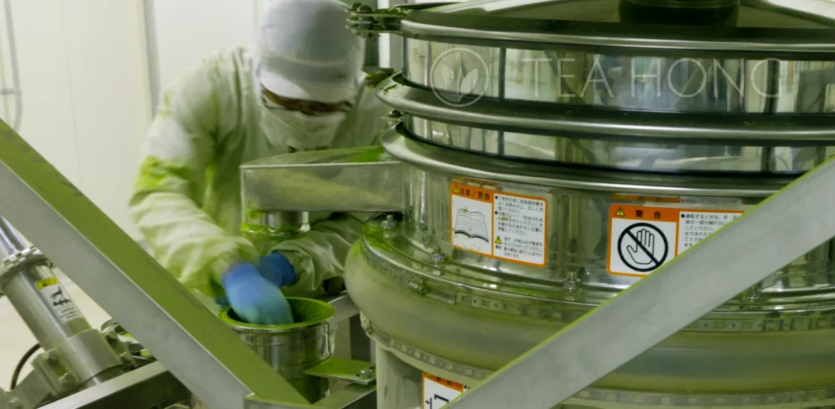 a technician in full protective clothing working on a matcha grinder