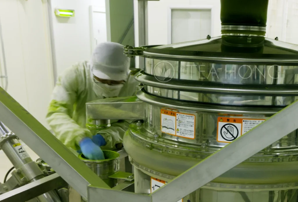 a technician clearing a tube for feeding freshly grounded matcha through a sieving machine