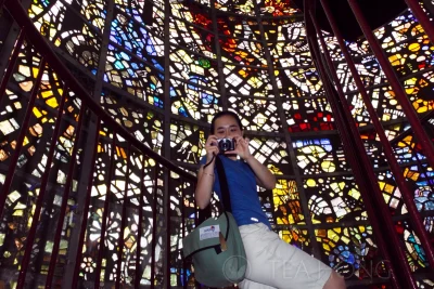 My girlfriend pointing the camera at me on the stairway inside a stained glass tower