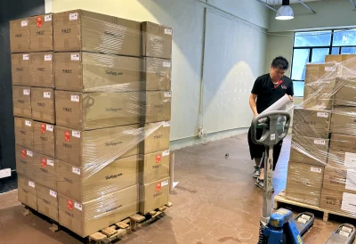 worker wrapping a pallet load of cartons before moving them