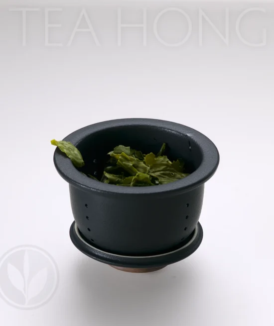 Infuser of the Easy Life Traveller's Tea set An infuser standing on the reversed side of the lid, holding infused tealeaves inside