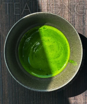 top view of a bowl of matcha in an intense green colour, with a swirl of thin foam on the surface.