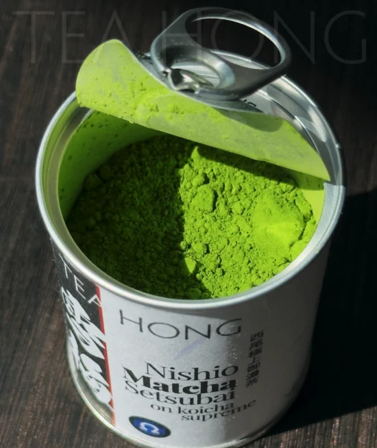 Nishio Matcha supreme open tin can A pull top tin can with the cover pulled, revealing the green tea powder inside
