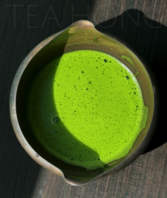 Nishio Matcha supreme usucha a dark colour chawan holding a matcha liquor with a dense layer of tiny foams in bright green colour