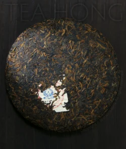 a well formed compressed tea discus with golden flush densely packed together with very dark colour tea leaves