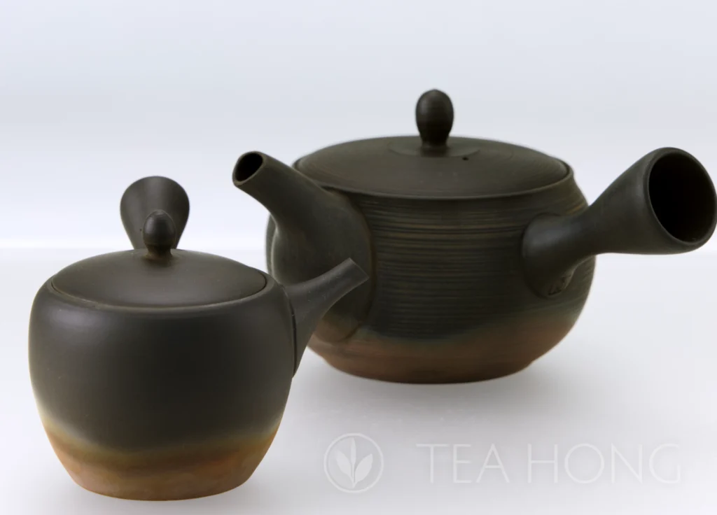 Two stoneware kyūsus, each of a different size and shape, produced using the same firing technique for a dark matte surface in the upper body and an uneven dark red clay colour in the lower part.