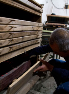 Old Master Wang checking the coal ash fire to ensure consistent baking for this round of production. Master Wang reaching into the charcoal tray
