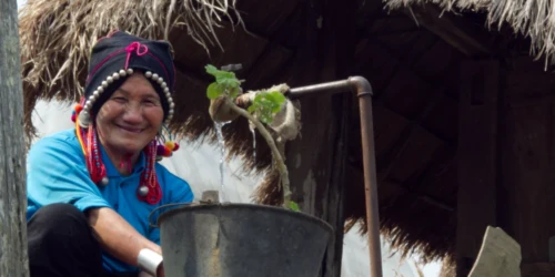 A woman of an indigenous tribe — Tai — smiles to us as we walk by her simple home