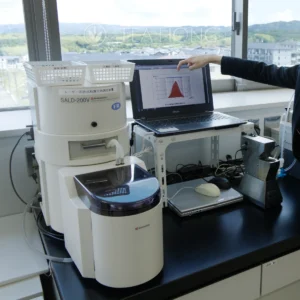 A laboratory is set up on a floor above our Uji matcha's grinding workshop to monitor the various quality parameters of the production. Here the reader displays the range of size difference in a batch and the distribution in relative volume. Particle size distribution monitoring set up in an office overlooking at the tea fields in Uji